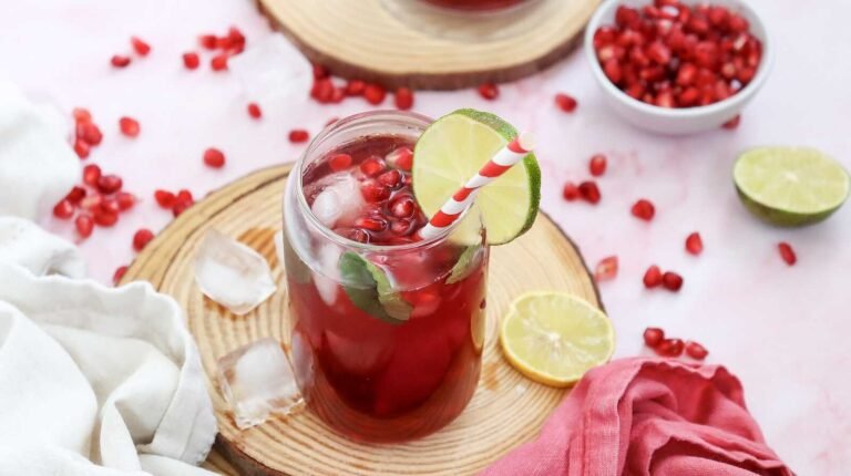 Pomegranate Fizz Mocktail with lime slice, mint, and pomegranate seeds over ice