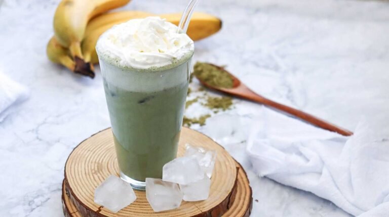 Iced green tea frappuccino with whipped cream on a wooden board.